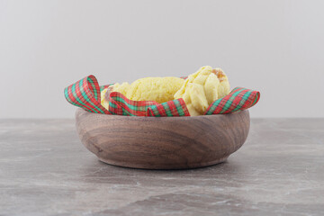 Cookies and ribbons in a small bowl on marble background