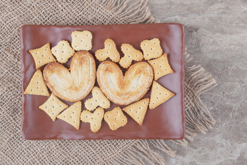 Flaky cookies and crackers bundles on a platter on marble background