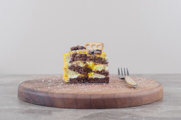Biscuit and anise on a cake slice next to a fork on a board on marble background