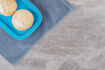 Crumbly cookies on a blue platter on a piece of fabric on marble background