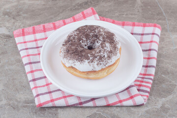 A platter with a donut on a towel on marble background