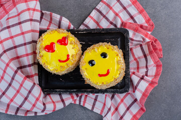 Two slices of homemade cake with yellow glaze on dark plate