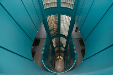 Stairwell with large glass pave skylight and blue metal railings