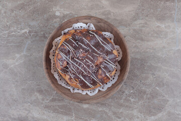 Chocolate coated cake in a wooden platter on marble background