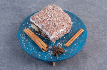 Tiramisu cake with cinnamon sticks on blue plate