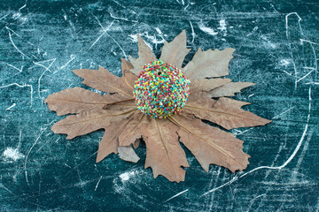 Delicious fresh doughnut with sprinkles on a leaves