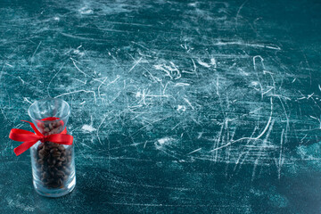 A glass jug full of coffee beans on a blue background