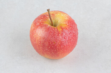 Red apple with water drops on stone background