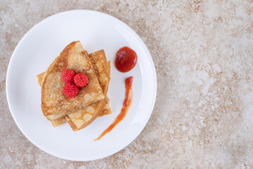 A white plate with pancakes and berries