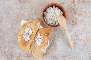 Roll pancakes with cottage cheese and a wooden spoon