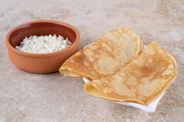 Roll pancakes with cottage cheese and a clay bowl