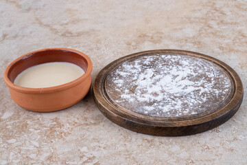 A brown plate of flour and a clay bowl