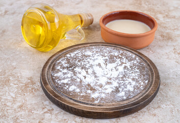 A brown plate of flour and a glass bottle of oil