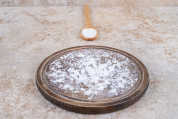 A brown plate of flour and a wooden spoon of sugar