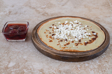 A wooden board of homemade thin fresh crepes with strawberry jam