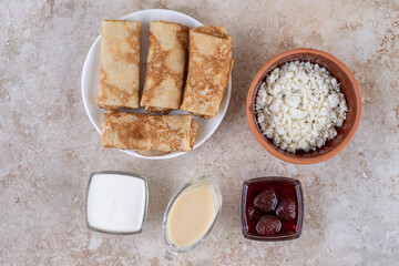 A white plate of tasty crepes and strawberry jam