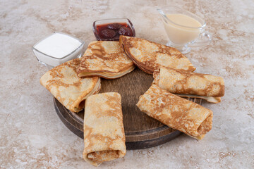 A wooden board of tasty crepes and strawberry jam