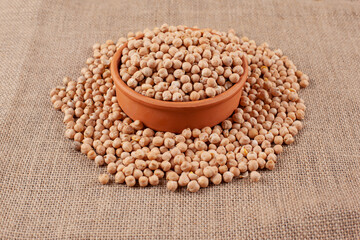 A clay bowl full of beans of peas on a sackcloth