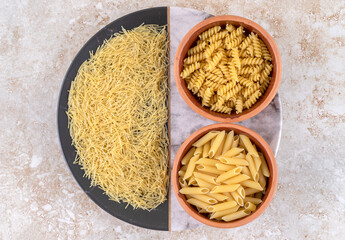 Various types of raw pasta on a marble background