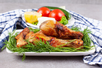Baked chicken legs with greens on a white plate