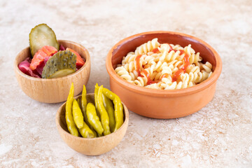 A clay bowl of delicious pasta with various vegetables