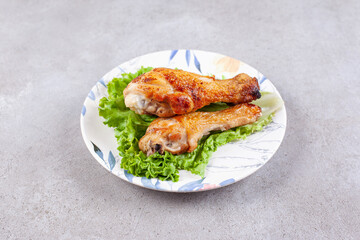 Grilled chicken legs meat with lettuce on white plate