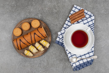 Desserts, cup of tea and cinnamon sticks on marble surface