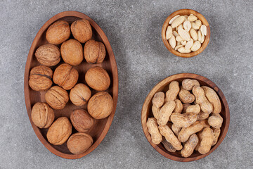 Plate of walnuts, peanuts and cashew on marble surface