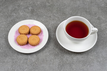 Delicious round biscuits and cup of tea on marble surface