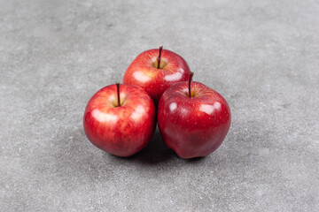Three red apples on marble background