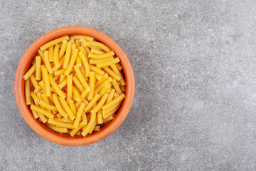 Bunch of raw macaroni in wooden bowl