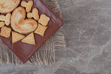 Flaky cookies and crackers bundles on a platter on marble background