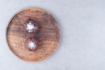 Chocolate cupcakes on a wooden tray on marble background