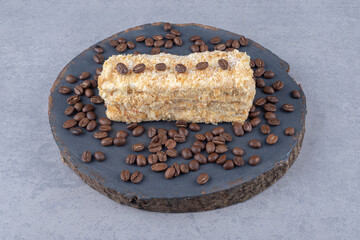 Small cake and coffee beans on a wooden board on marble background