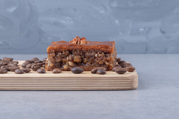Bakhlava and coffee beans on a wooden board on marble background