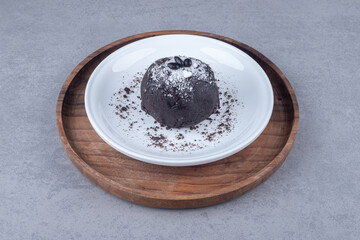 Chocolate cake on a platter on a wooden tray on marble background