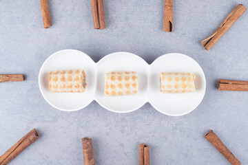 Small cookies on a serving platter surrounded with cinnamon sticks on marble background