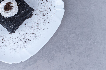 A slice of chocolate cake on a platter on marble background