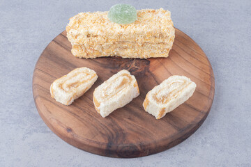 Cake roll and slice on a wooden board on marble background