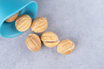 Bundle of caramel filled cookie balls spilled out of a small bowl on marble background