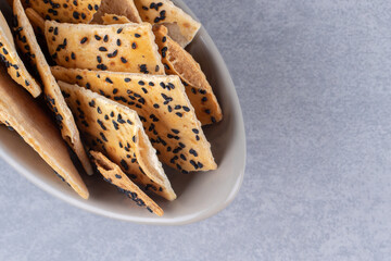 Sesame coated bread slices in a bowl on marble background