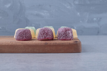 Marmelades arranged on a wooden board on marble background
