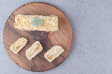 Cake roll and slice on a wooden board on marble background