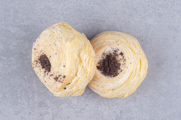 Two flaky cookies displayed on marble background