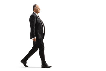 Full length profile shot of a mature businessman in a black suit walking