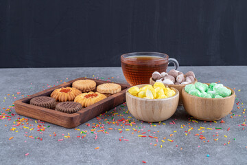 Cookies, candy bowls and a cup of tea on marble background