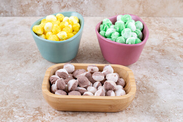 Bowls with cocoa, mint and lemon flavored candies on marble background