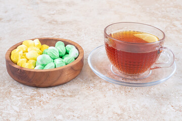 Mint and lemon flavored candies next to a cup of tea on marble background