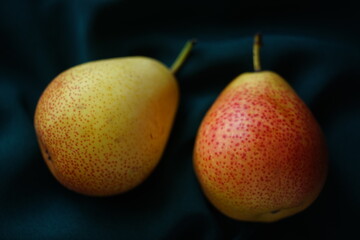 Two yellow orange pears on a dark green table