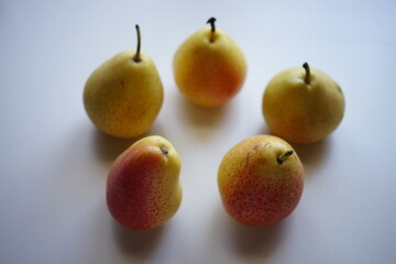 Five yellow orange pears on a white table
